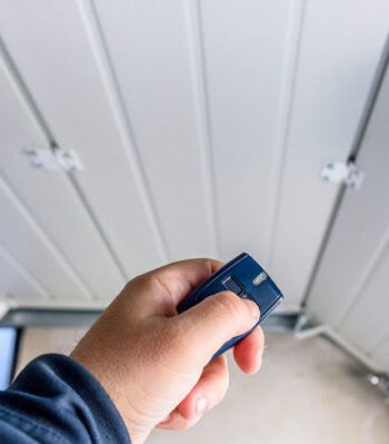 A person is holding a remote control in their hand in front of a white wall.