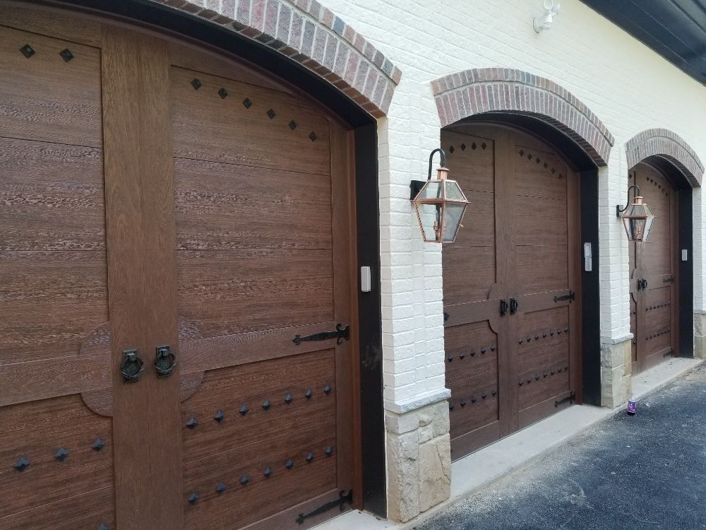 A row of wooden garage doors on a white brick building.